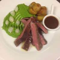 Steak z hovězího pupku připravený metodou sous vide s hráškovým purée, cibulkami, pečenými brambůrkami Grenaille a pepřovou omáčkou